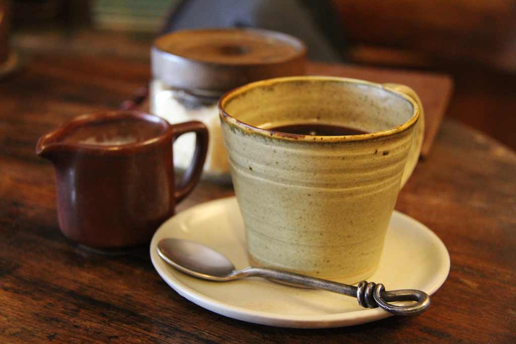 une tasse de thé en terre cuite et un pot de sucre.
